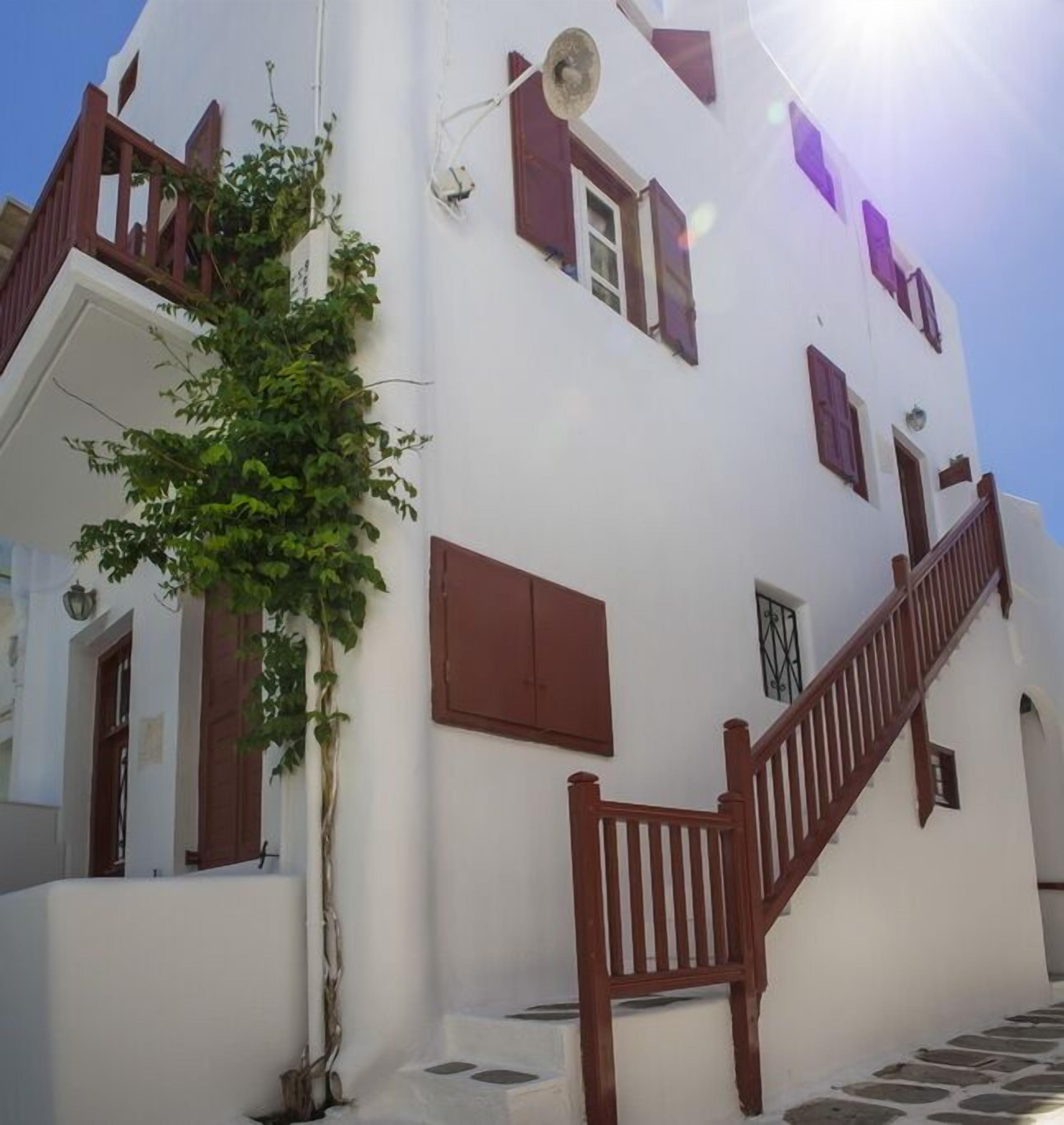 A white building with a wooden staircase and a potted plant.