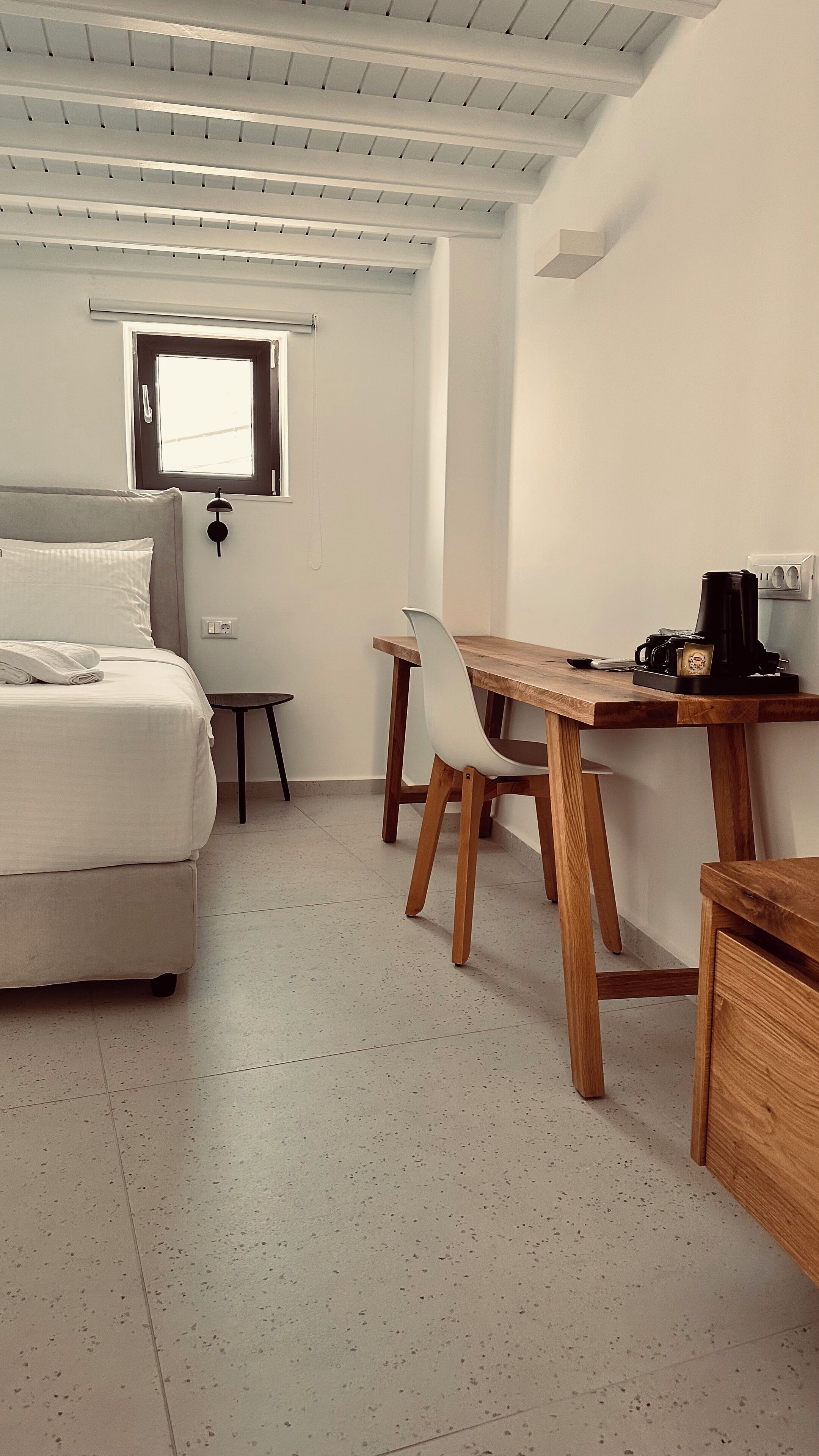 Una camera da letto con un letto, un tavolino, una sedia, una scrivania con una macchina del caffè e una finestra.