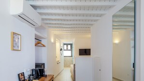 A modern kitchen with a built-in oven, a coffee machine, and a small dining area with a wooden table and chairs. - Alana Mykonos (Mykonos)