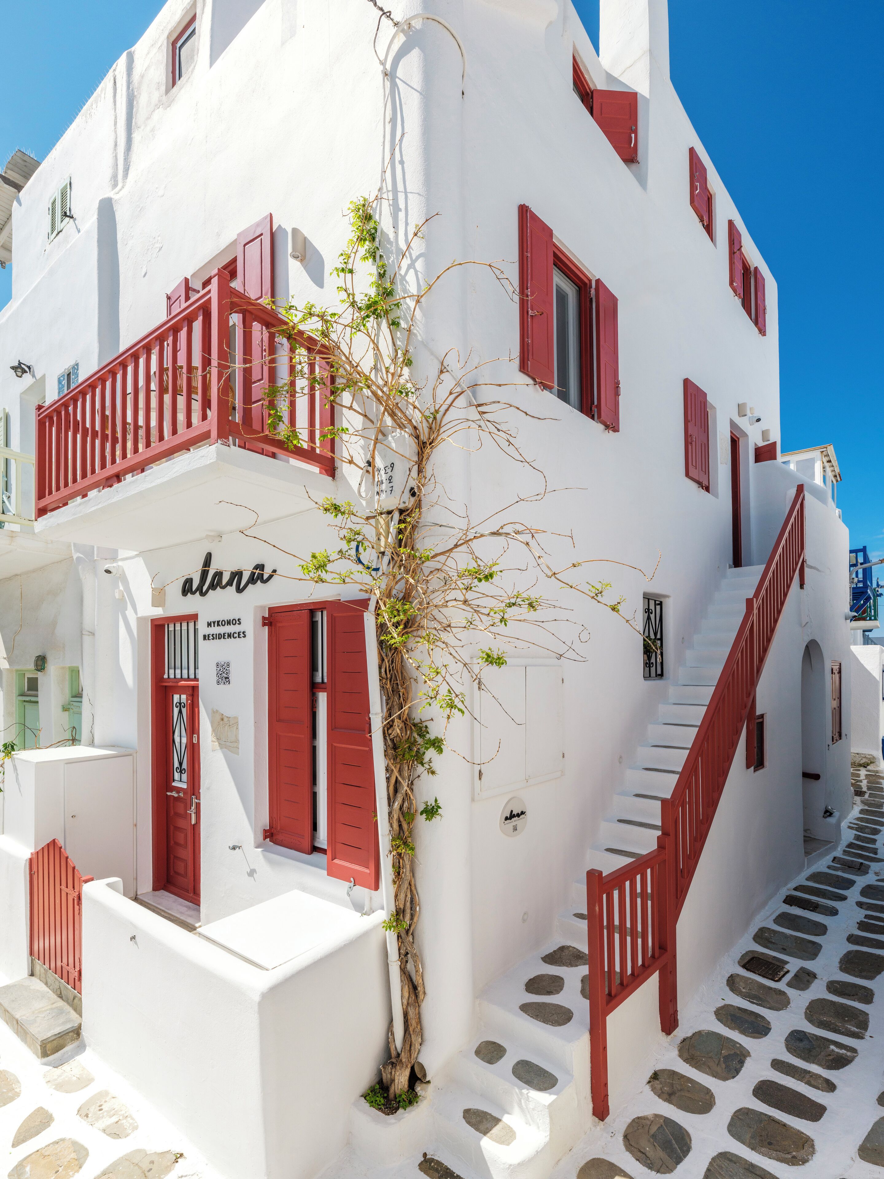 A white building with red shutters and a staircase.