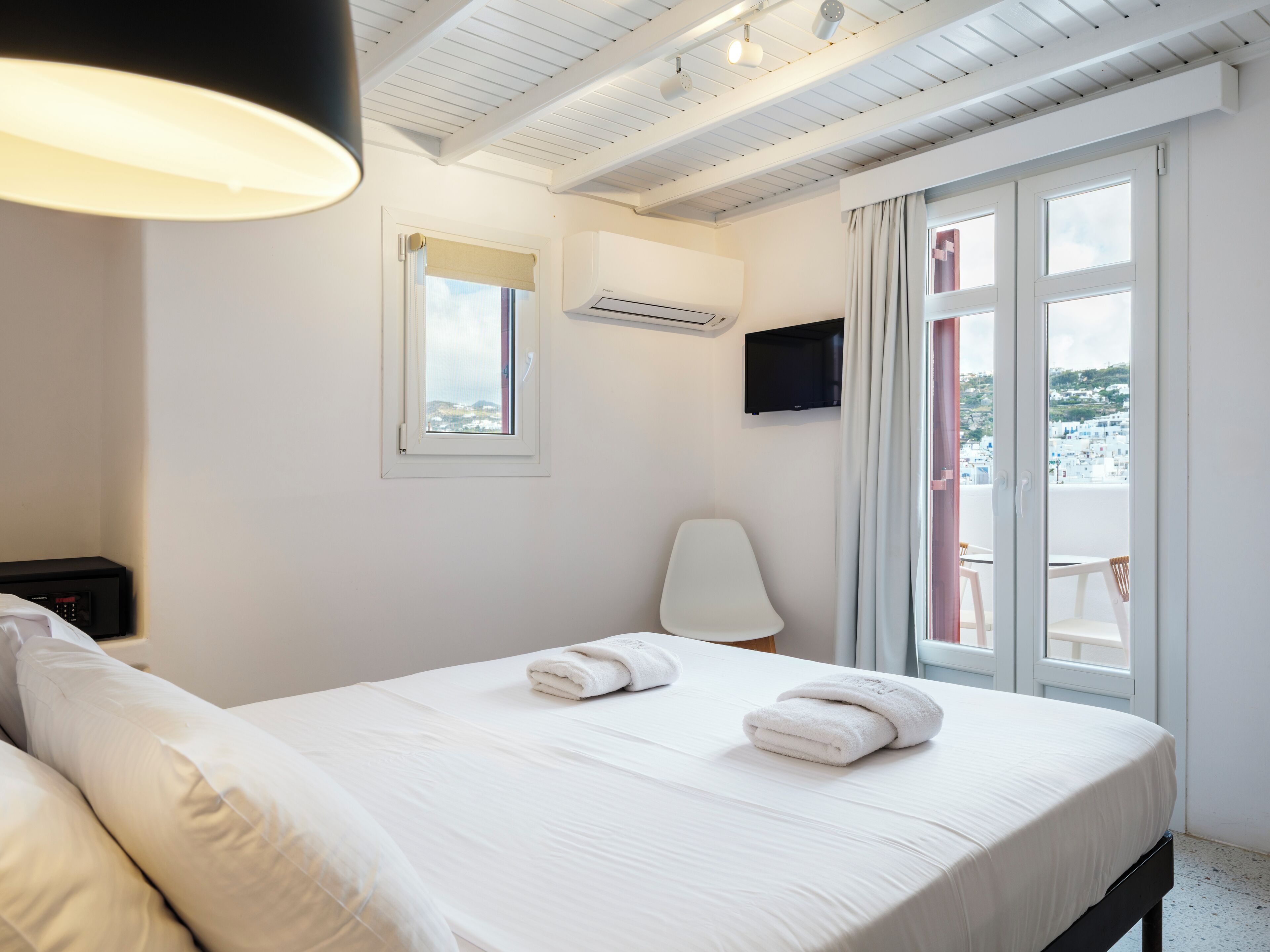 Habitación de hotel con una cama grande, televisión montada en la pared y ventana con vistas a la ciudad.