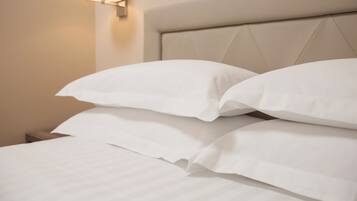 Cama bem arrumada com lençóis brancos e cabeceira com padrão de losangos.