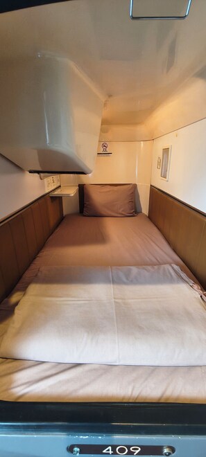 A narrow, single-bed cabin with a headboard, a pillow, and a control panel with the number 409. - THE NELL UENO OKACHIMACHI - Caters to Men (Tokyo)