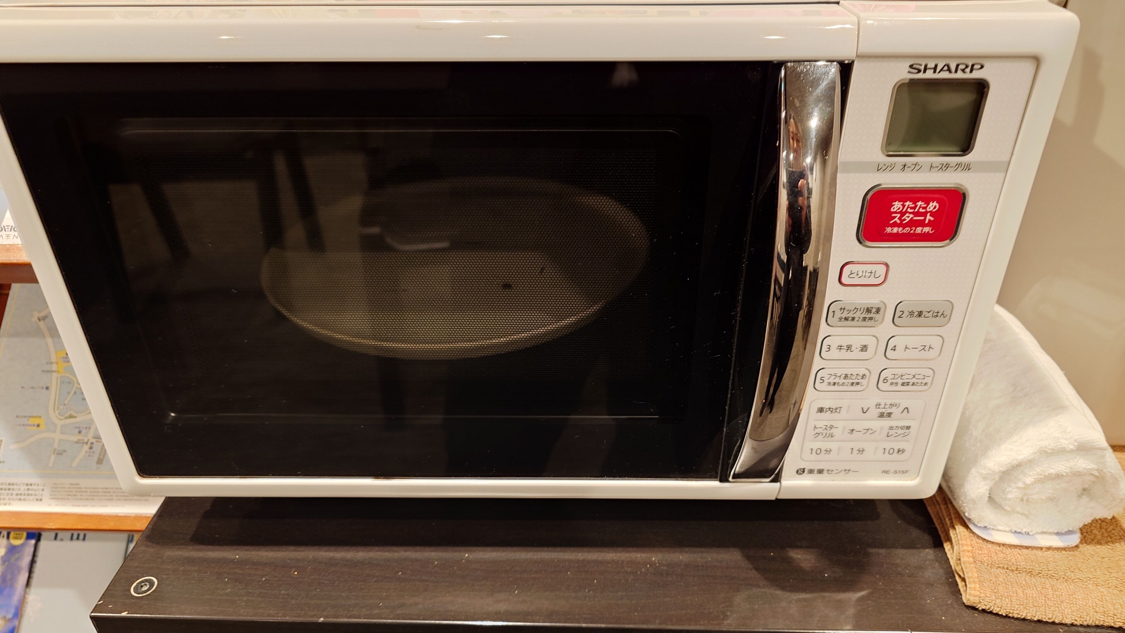 Een witte Sharp magnetron met een digitaal display en verschillende bedieningsknoppen.