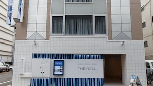 Un hôtel à la façade moderne, doté de grandes fenêtres et d’une enseigne publicitaire indiquant « The Nell ».