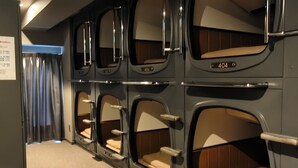 Une rangée de petits dortoirs individuels, numérotés 404, 403 et 402, avec des planchers recouverts de moquette et une grille d’aération au plafond.