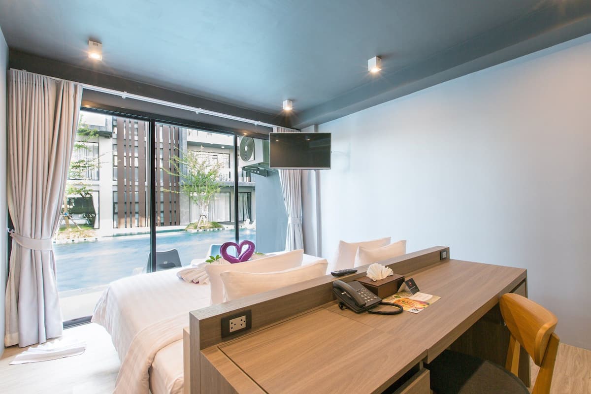 Une chambre d’hôtel équipée d’un lit, d’un bureau avec un téléphone et d’un téléviseur fixé au mur.