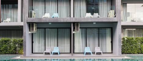 A modern hotel with a pool area, featuring a two-story structure, large windows, and outdoor seating by the pool.