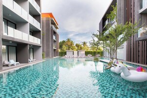 Un hotel moderno con piscina, sillones de descanso y un flotador decorativo con forma de unicornio.