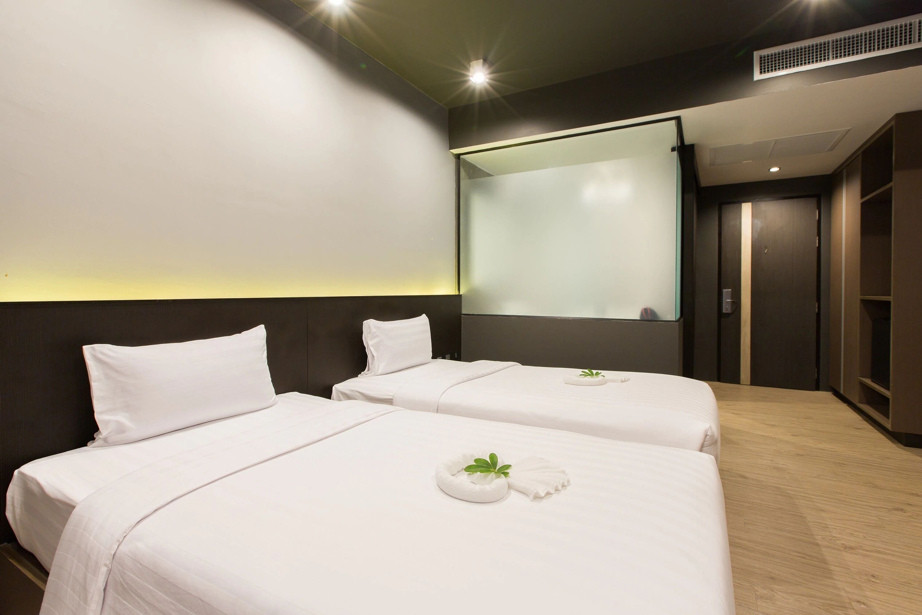 A hotel room with two beds, a large window, and a modern design.