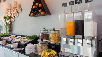 A buffet setup with various food items, including fruits, vegetables, and grains, along with juice dispensers.
