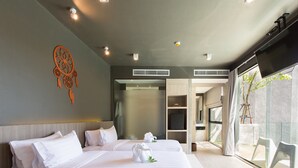 A modern hotel room with two beds, a dreamcatcher decoration, and a view of the outside through large windows.