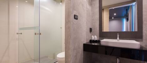 A modern bathroom with a glass shower enclosure, a white toilet, and a black sink with a mirror above it.