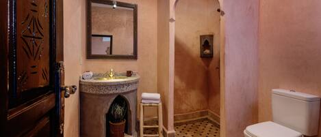 Ein Badezimmer mit Marmorwaschbecken, Toilette und Duschbereich.