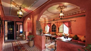 Un intérieur traditionnel avec un tapis à motifs, un coin salon agrémenté de coussins et un plafond décoratif.