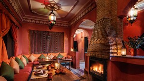 Un salon confortable avec une cheminée, des coussins à motifs et un décor traditionnel.