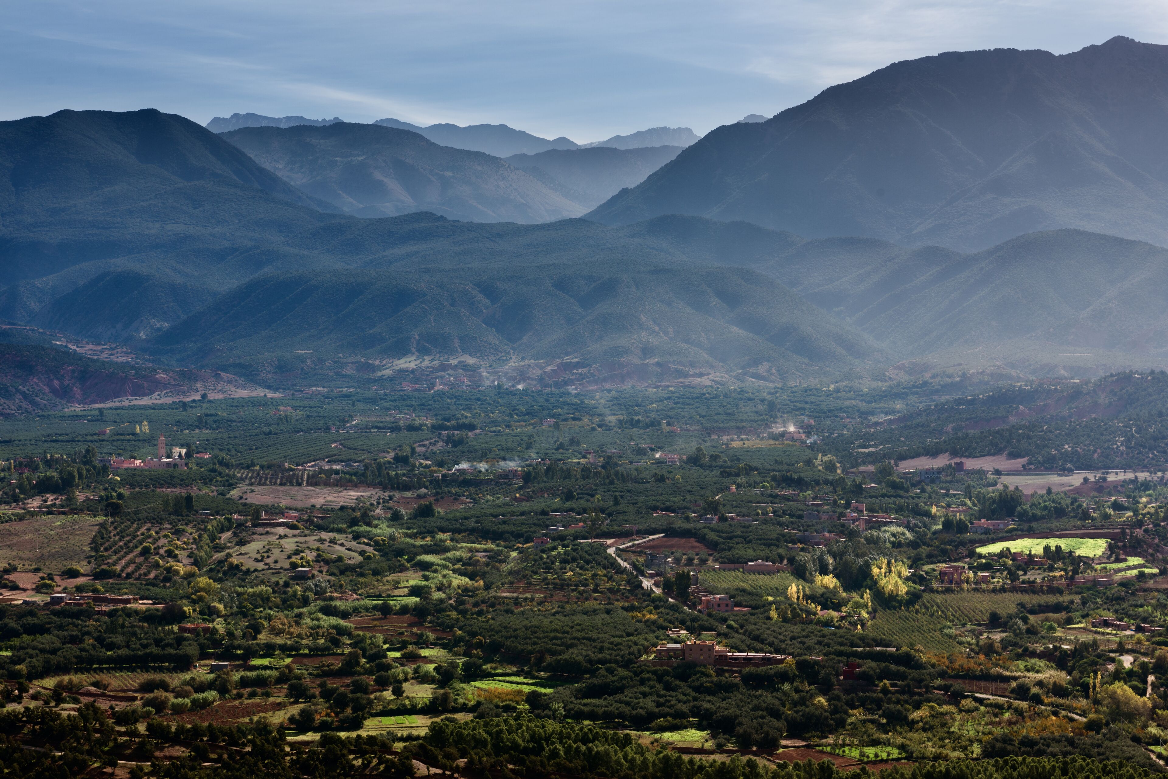 A mountainous landscape with a valley below, featuring terraced fields and scattered buildings.