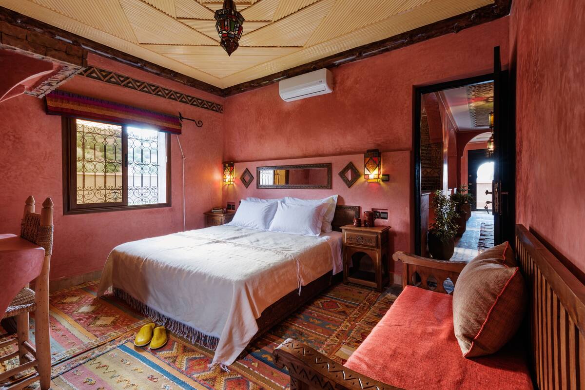 Une chambre à coucher comprenant un lit, une chaise, une table de chevet, un miroir et une fenêtre donnant sur un paysage agréable.