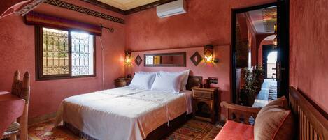 Una camera da letto con un letto, una sedia, un comodino, uno specchio e una finestra vista.