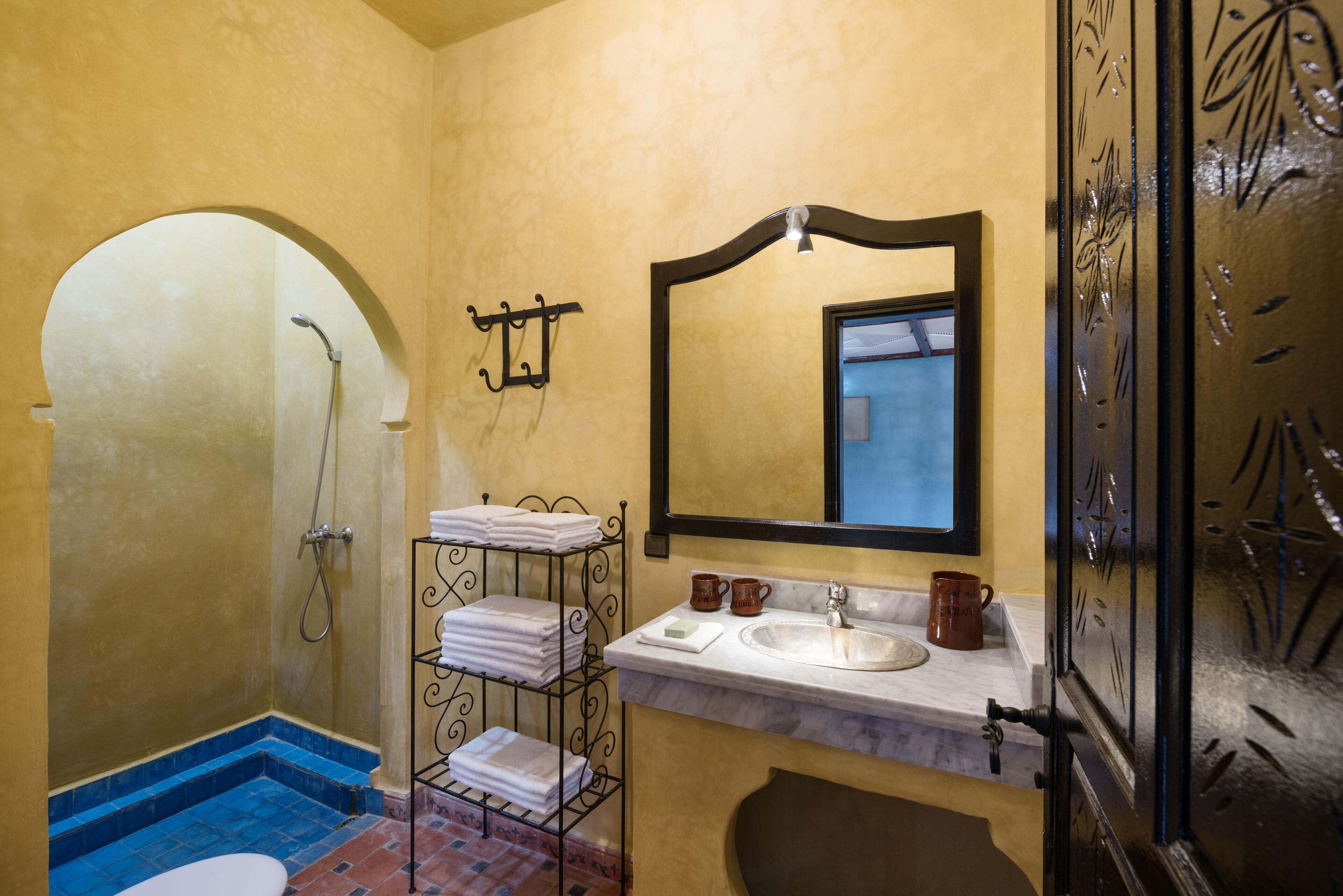 A bathroom with a shower, a sink, a mirror, and a towel rack.