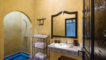 A bathroom with a shower, a sink, a mirror, and a towel rack.