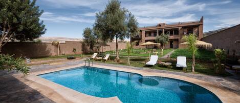 Una piscina al aire libre, sillones reclinables de piscina