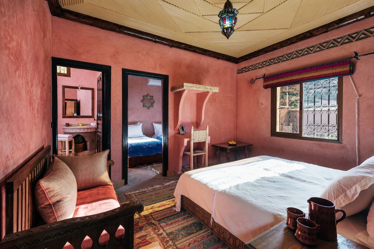 Une chambre avec un lit, une chaise, une petite table et une fenêtre donnant sur un beau paysage.