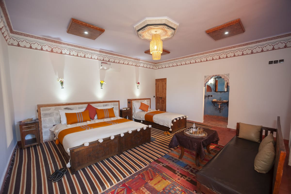 Une chambre avec deux lits, un canapé, une petite table et un miroir.