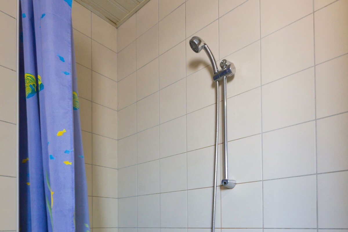 Un baño con bañera, ducha y cortina de motivos azules y amarillos.
