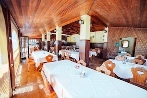 Een restaurant met houten plafond en gedekte tafels.