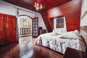 Een slaapkamer met een groot bed, houten wanden, een kroonluchter en een balkon.