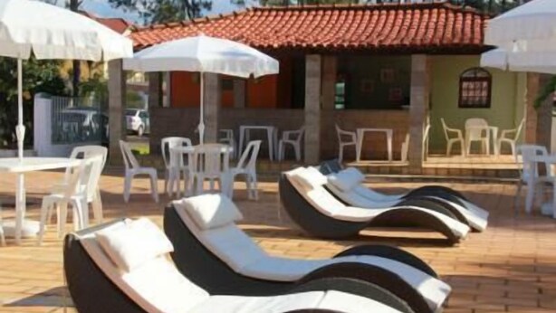 Buitenloungestoelen en -tafels, een gebouw met een pannendak en parasols.