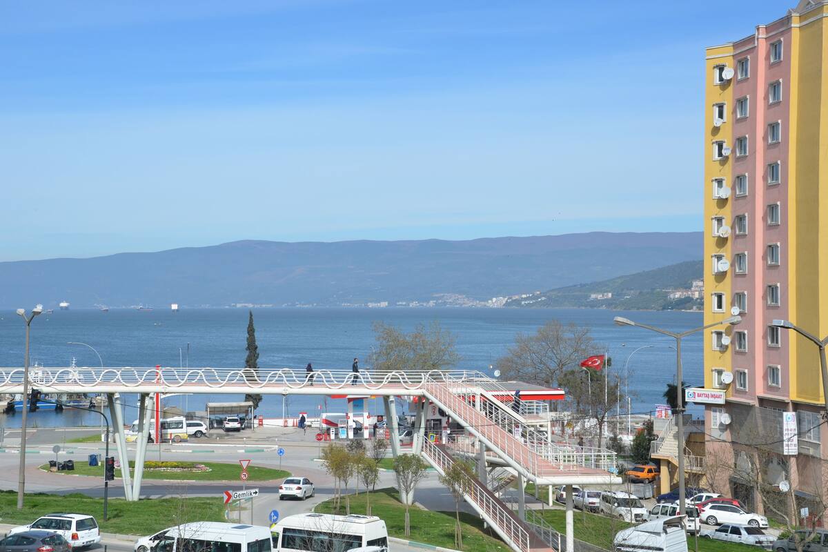 A coastal cityscape with a pedestrian bridge, a gas station, and a yellow building.