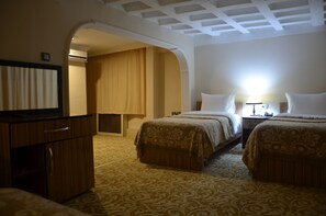 Une chambre d’hôtel avec deux lits, une télévision, un bureau et une armoire.