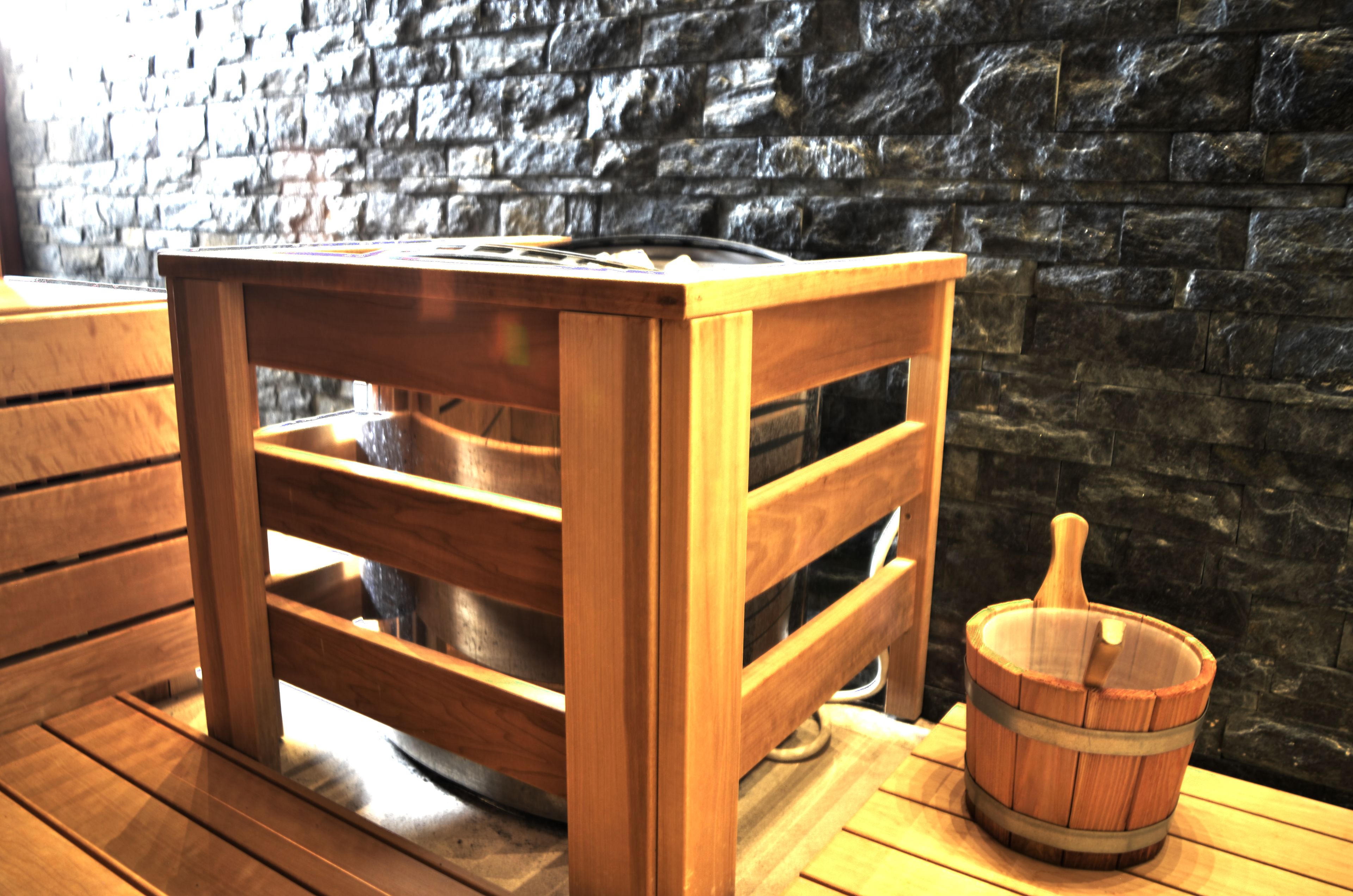 A wooden table with a metal tray, a wooden bucket, and a stone wall background.