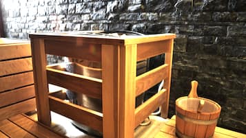 A wooden table with a metal tray, a wooden bucket, and a stone wall background.