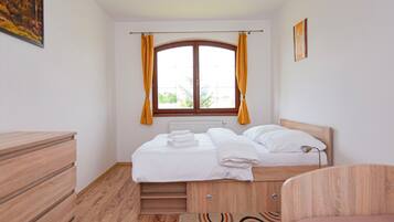 Un dormitorio con cama, cómoda de madera y ventana con cortinas.