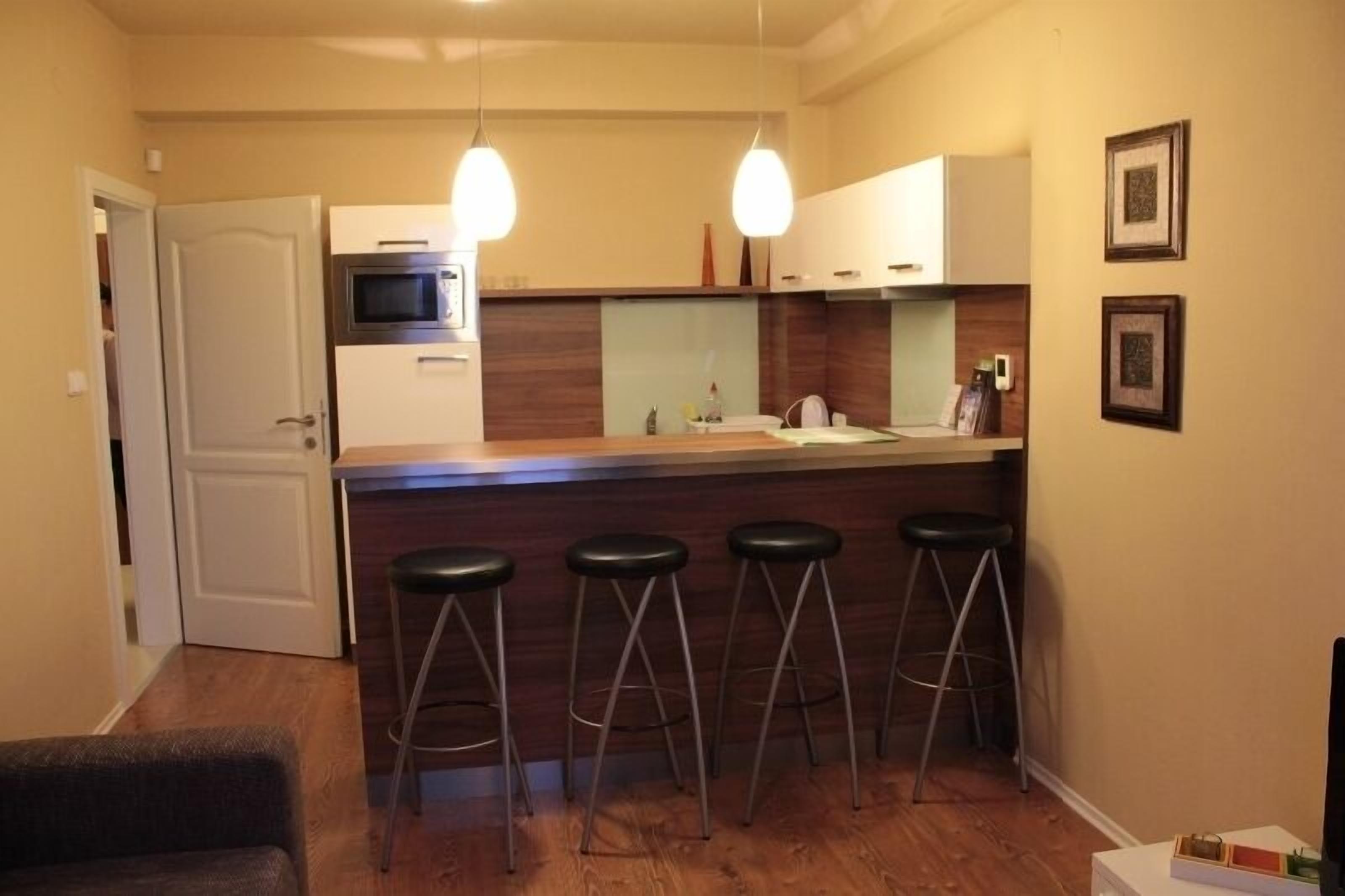 A compact kitchen with a central island, bar stools, and pendant lighting.
