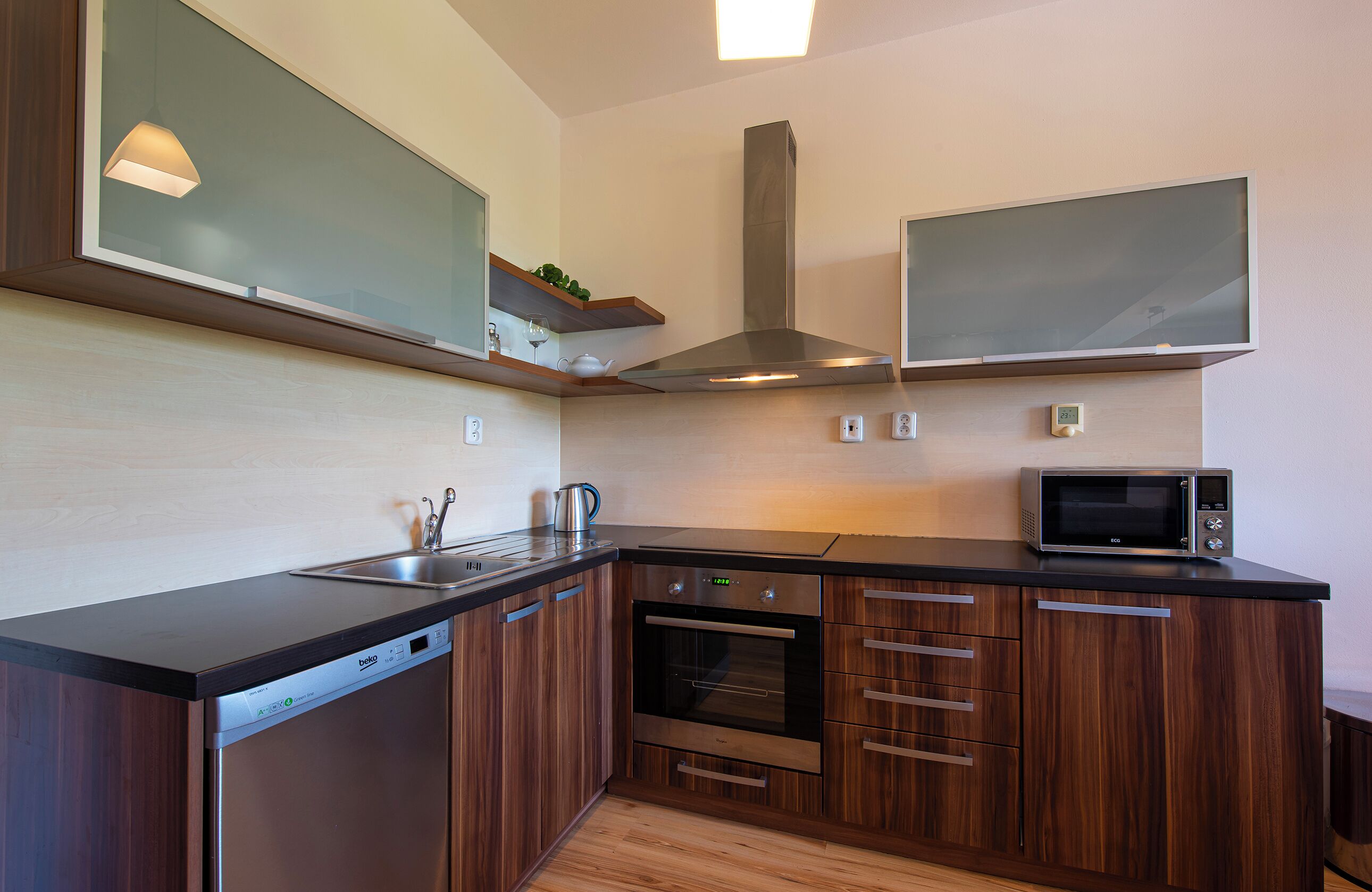 A modern kitchen with wooden cabinets, a built-in oven, a microwave, and a dishwasher.