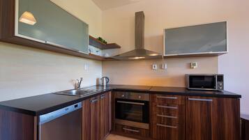A modern kitchen with wooden cabinets, a built-in oven, a microwave, and a dishwasher.