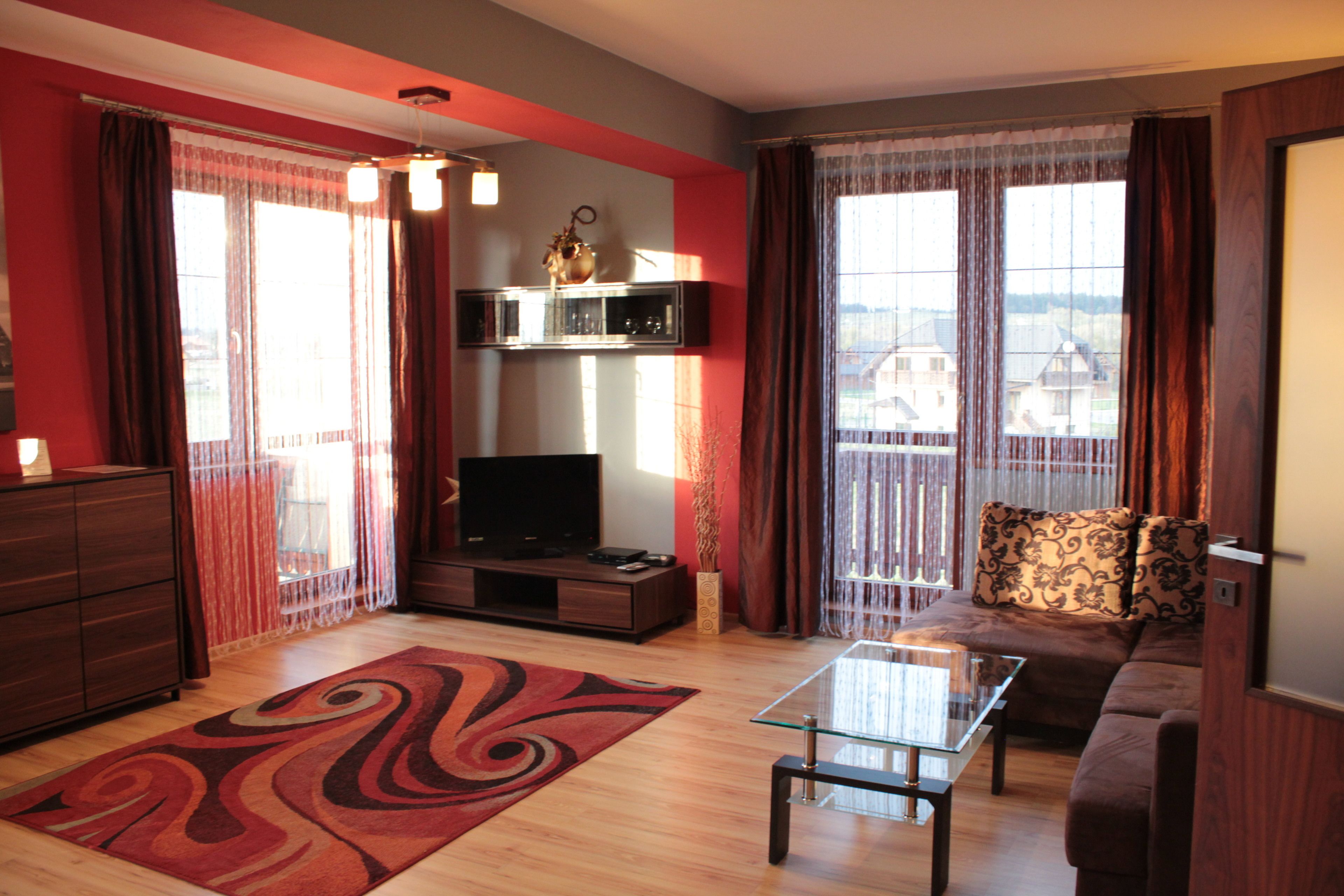 A living room with a sofa, a glass coffee table, a TV, and a decorative vase.