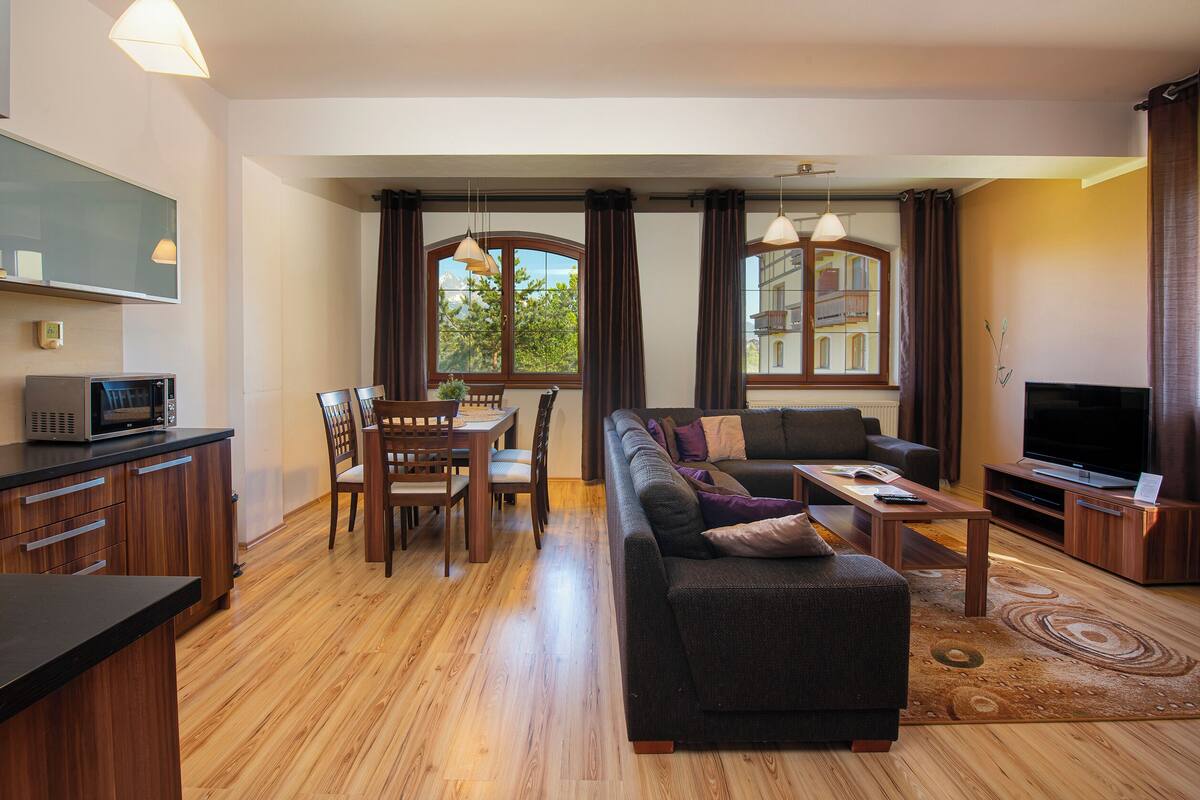 A modern living room with a sofa, television, and dining area.