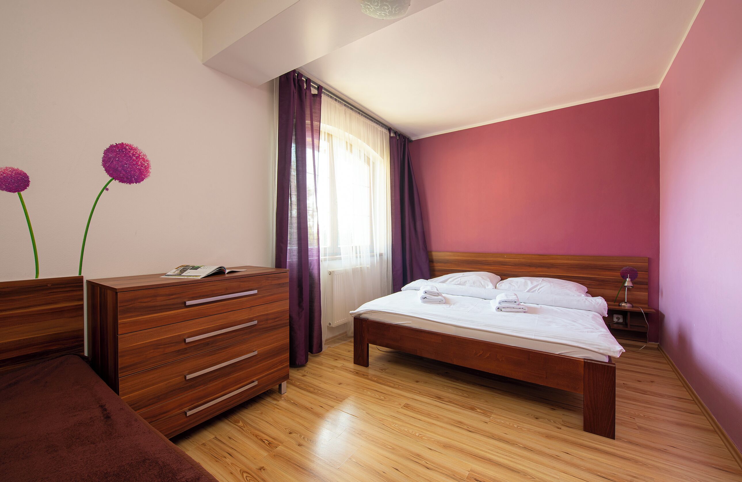 A bedroom with a wooden bed, a wooden dresser, and a nightstand.