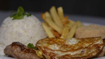 Une assiette contenant du riz, des frites, une galette de viande et un œuf frit.