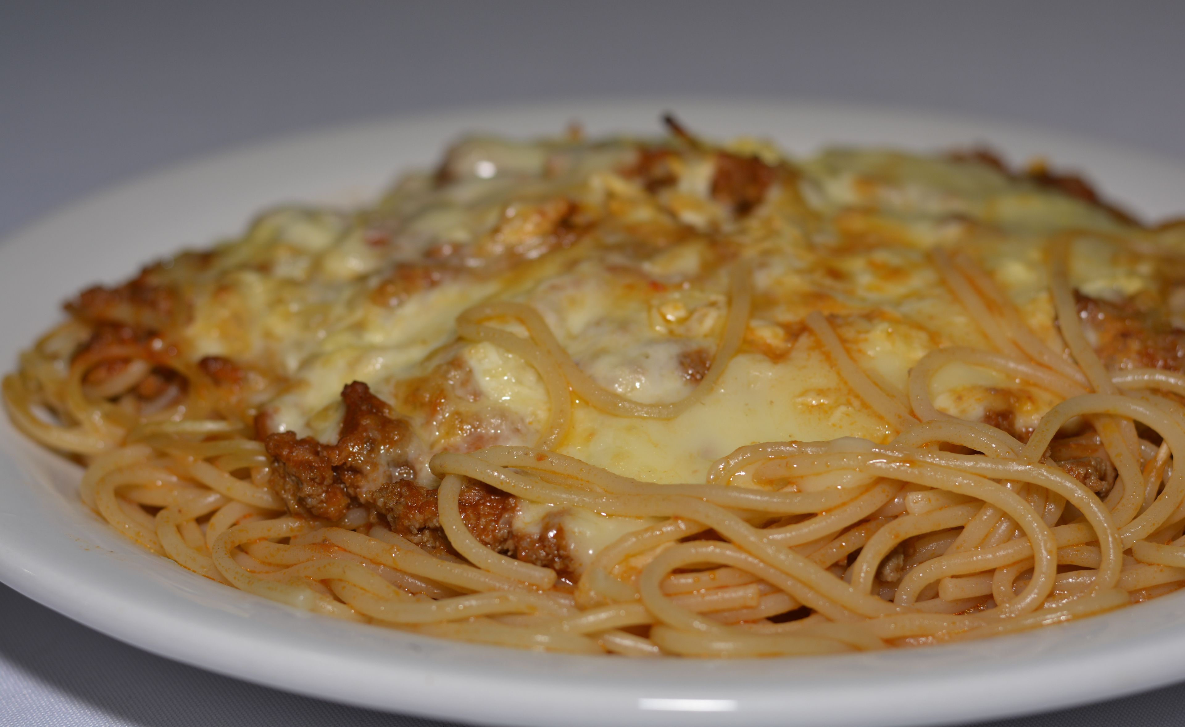 A plate of spaghetti with meat and melted cheese.