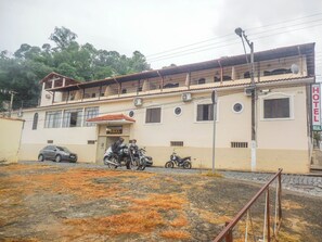 Un hotel con balcón, una señalización y motocicletas estacionadas.