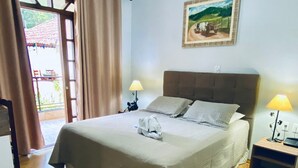 Een slaapkamer met een bed, een plafondventilator, een schilderij en een raam met gordijnen.