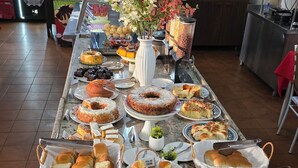 Een buffet met diverse gebakjes en een drankkoeler op de achtergrond.
