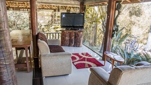 Una sala de estar con televisor, dos sofás, una mesa de centro y una mesa de comedor.