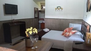 A hotel room with a bed, bedside table, TV, and a small kitchenette. - Pousada Campestre São Lourenço (Sao Lourenco)